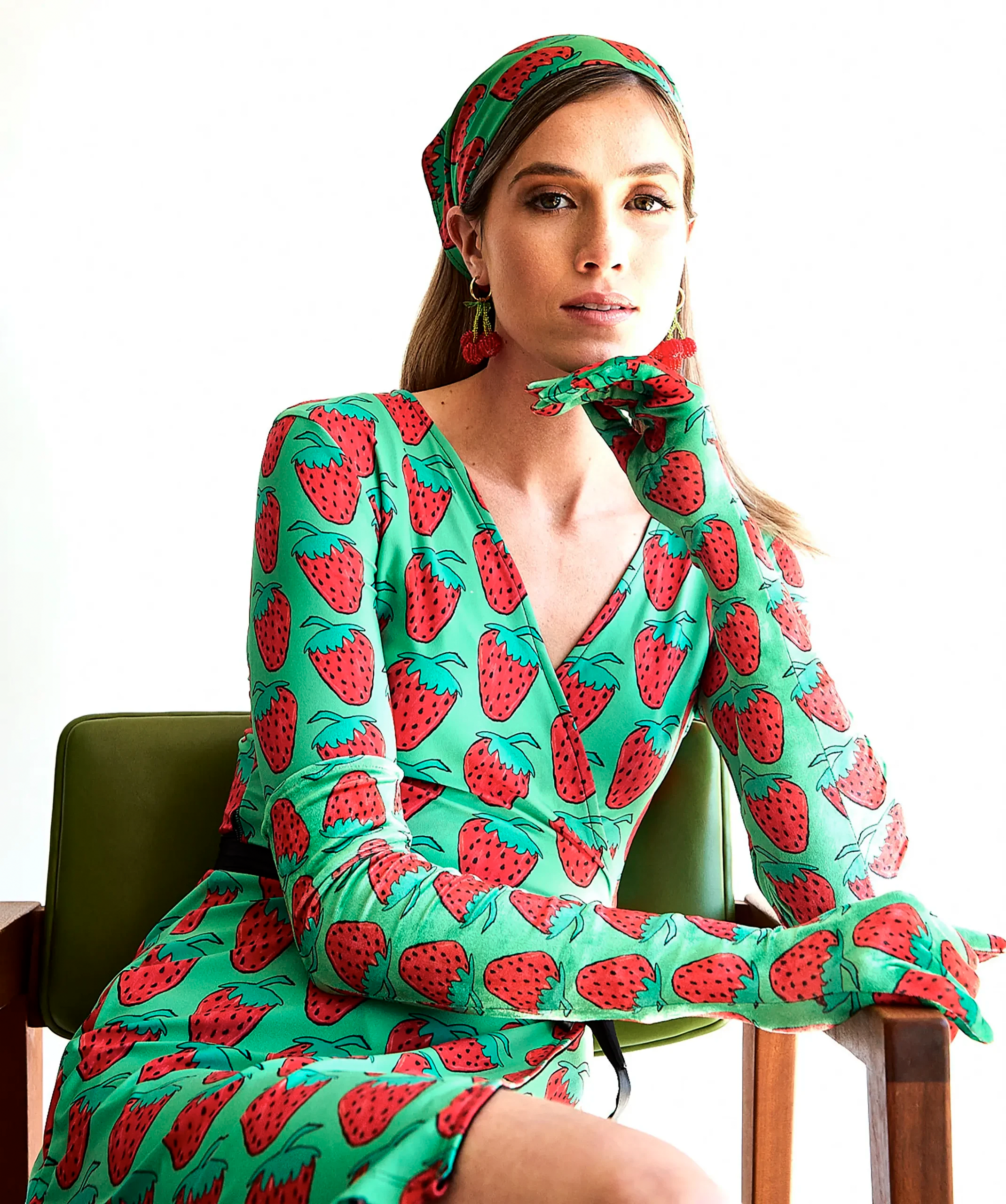 Seated model wearing green strawberry-print opera gloves with the matching dress and headscarf