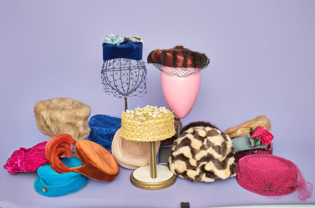 Vintage hats arranged together: a blue veiled hat, a yellow pillbox and a leopard-print hat