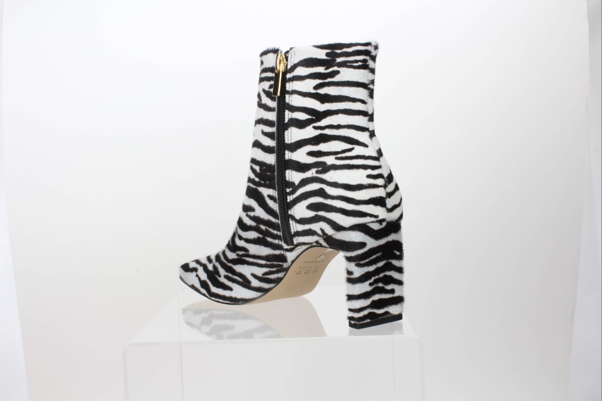 Rear angled view of a Carrano black-and-white zebra-print calf-hair ankle boot, showing the inner zipper, covered heel and part of the sole.