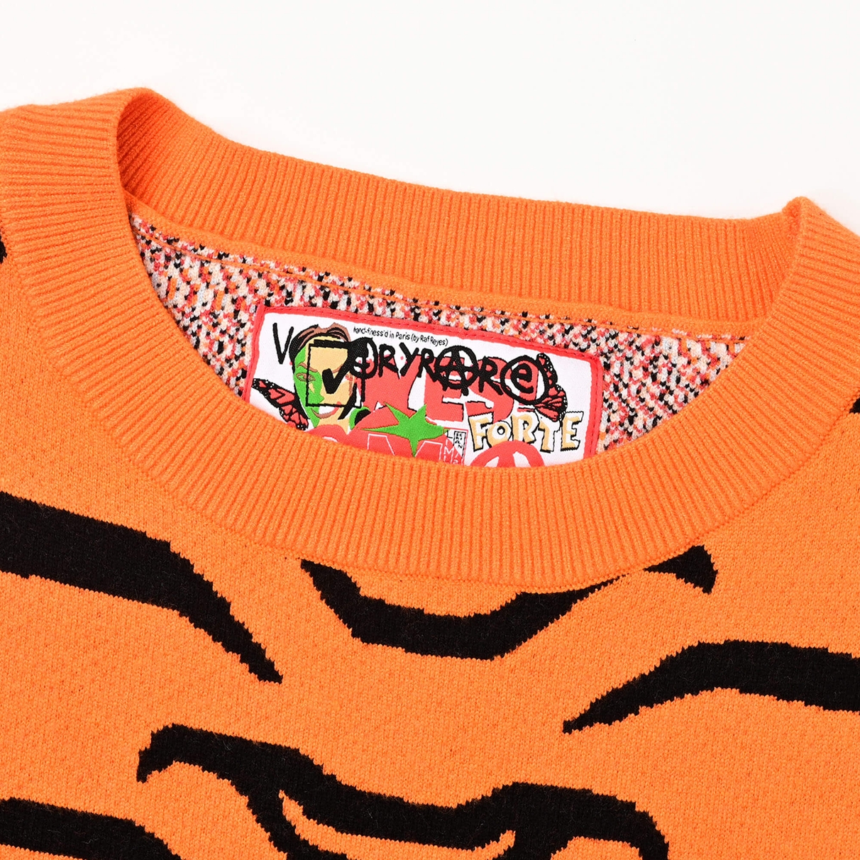 Close view of the Tiger Rug crewneck orange ribbed neckline and colourful VERYRARE neck label