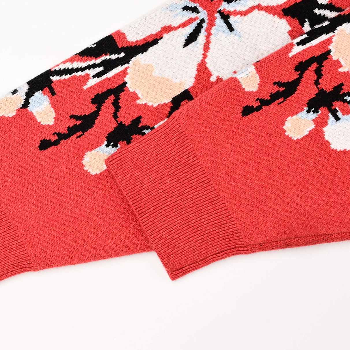 Close view of the Tiger Rug coral-red ribbed sleeve cuff and floral jacquard