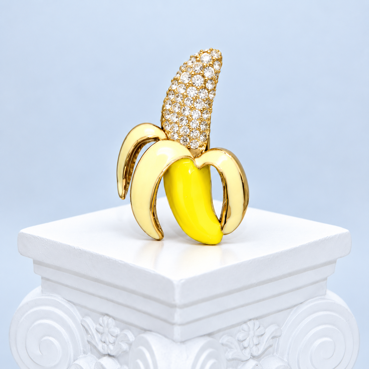 Straight front view of the Mio Queena yellow and ivory enamel banana brooch with clear rhinestones