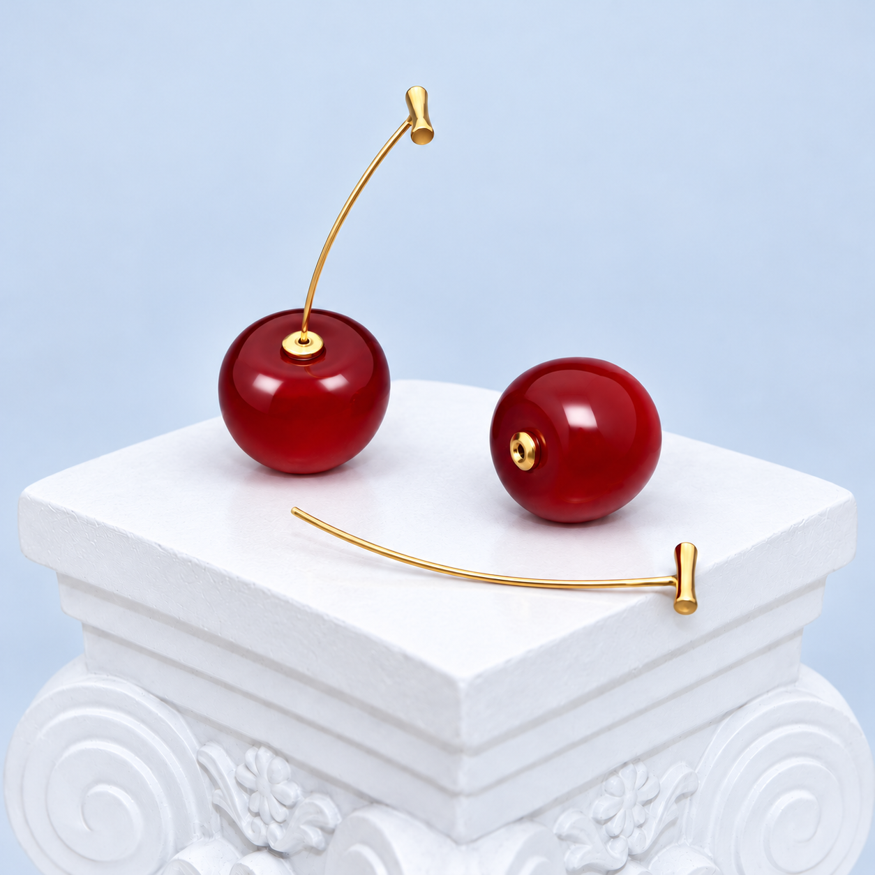 Mio Queena cherry earring detail showing one assembled earring, a loose red resin cherry and its separate gold-plated stem