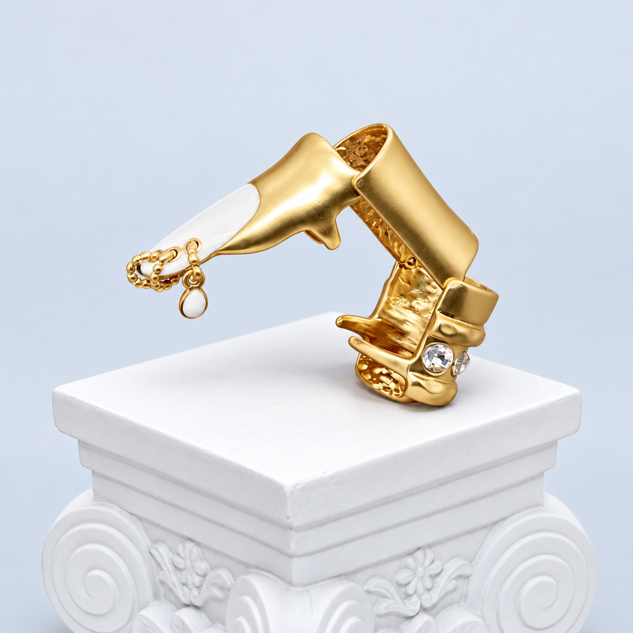 Bent side view of the Mio Queena White enamel finger ring, showing its articulated gold-tone sections, open underside and dangling chain with one white drop.
