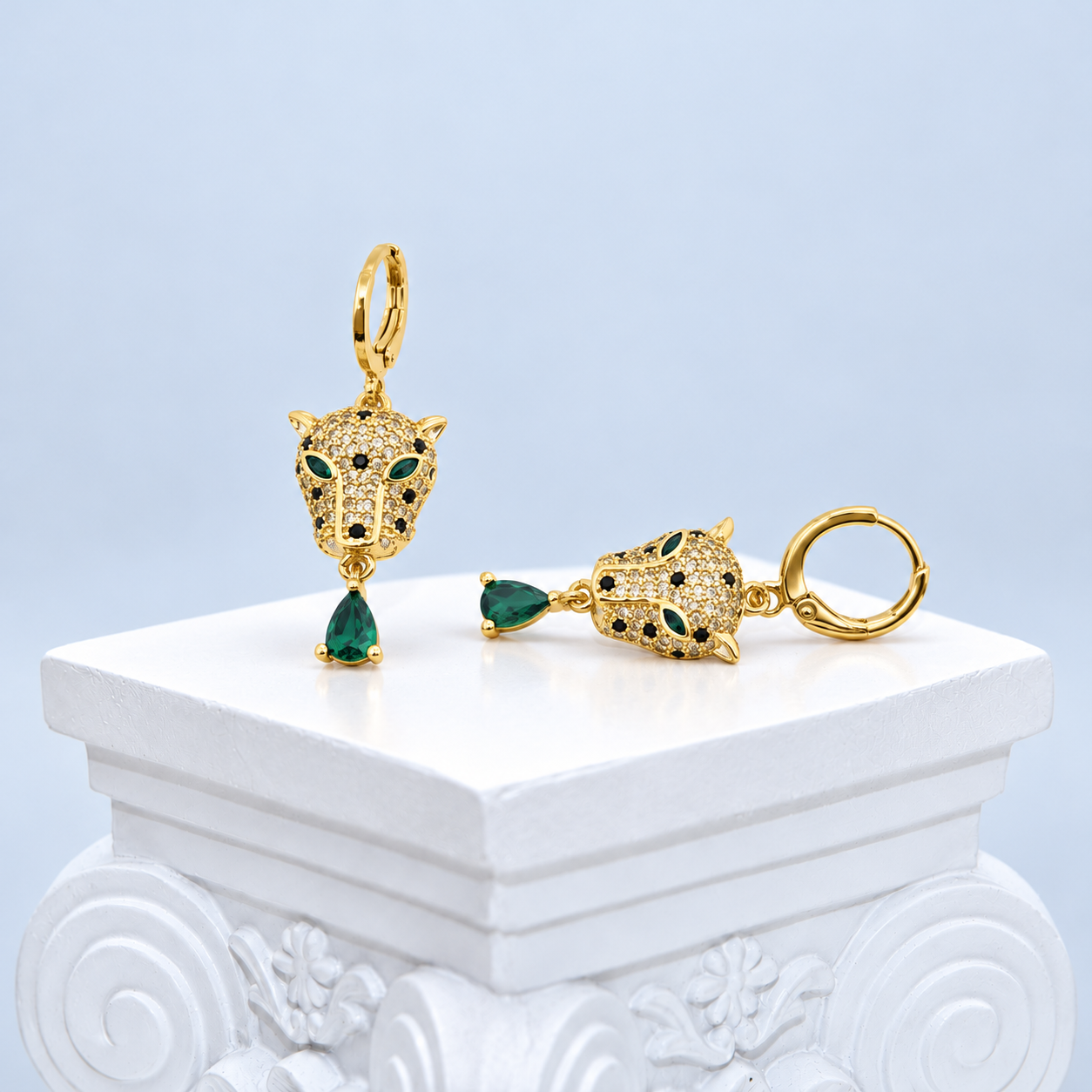 Opposed front views of the Mio Queena leopard earrings with complete hinged hoops and green teardrop drops