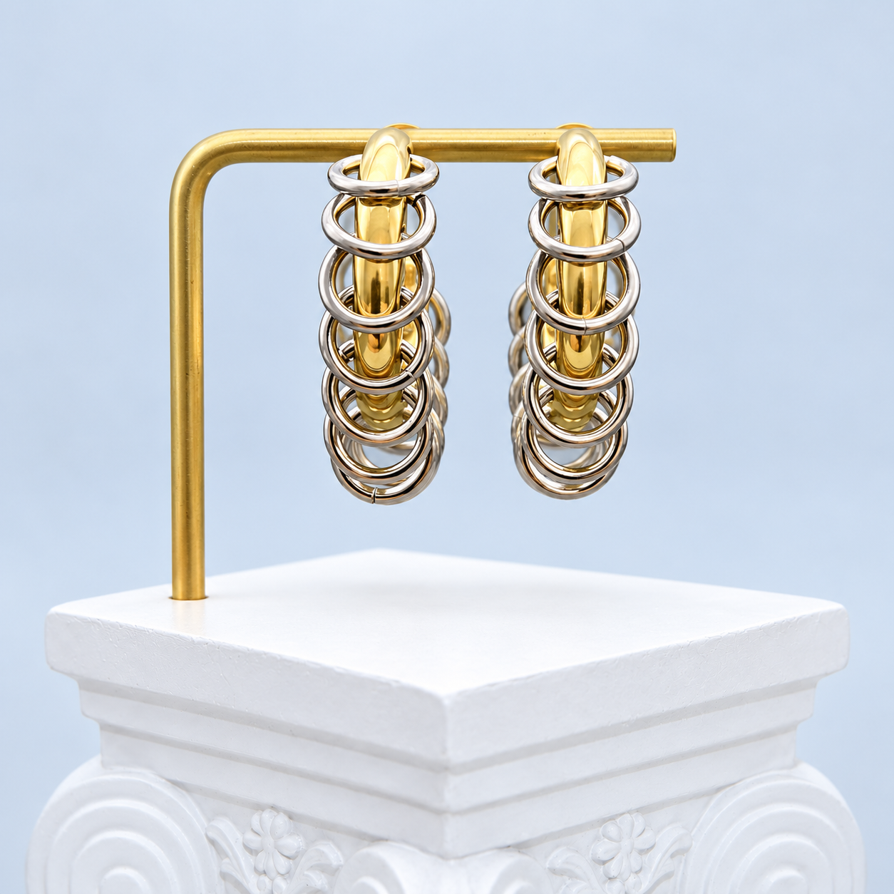 Edge-on view of both Mio Queena two-tone hoop earrings, showing the gold-plated curves and overlapping silver-tone rings.