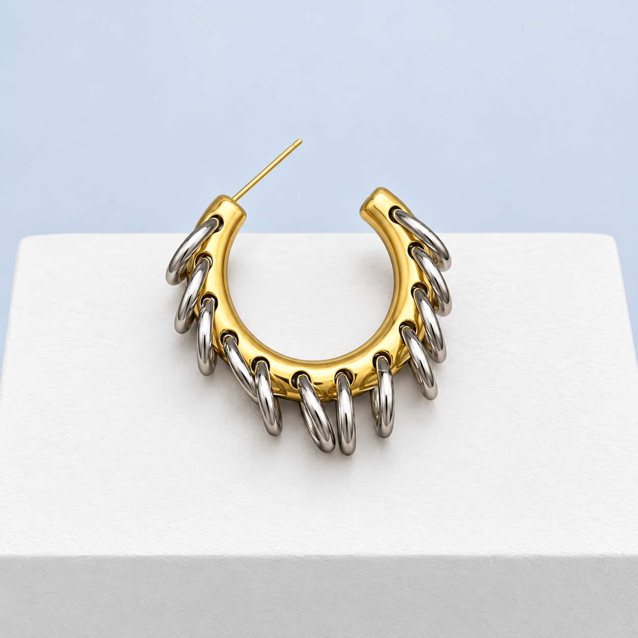 Single Mio Queena C-hoop earring with silver-tone ring fringe and visible straight post, on a white studio surface.